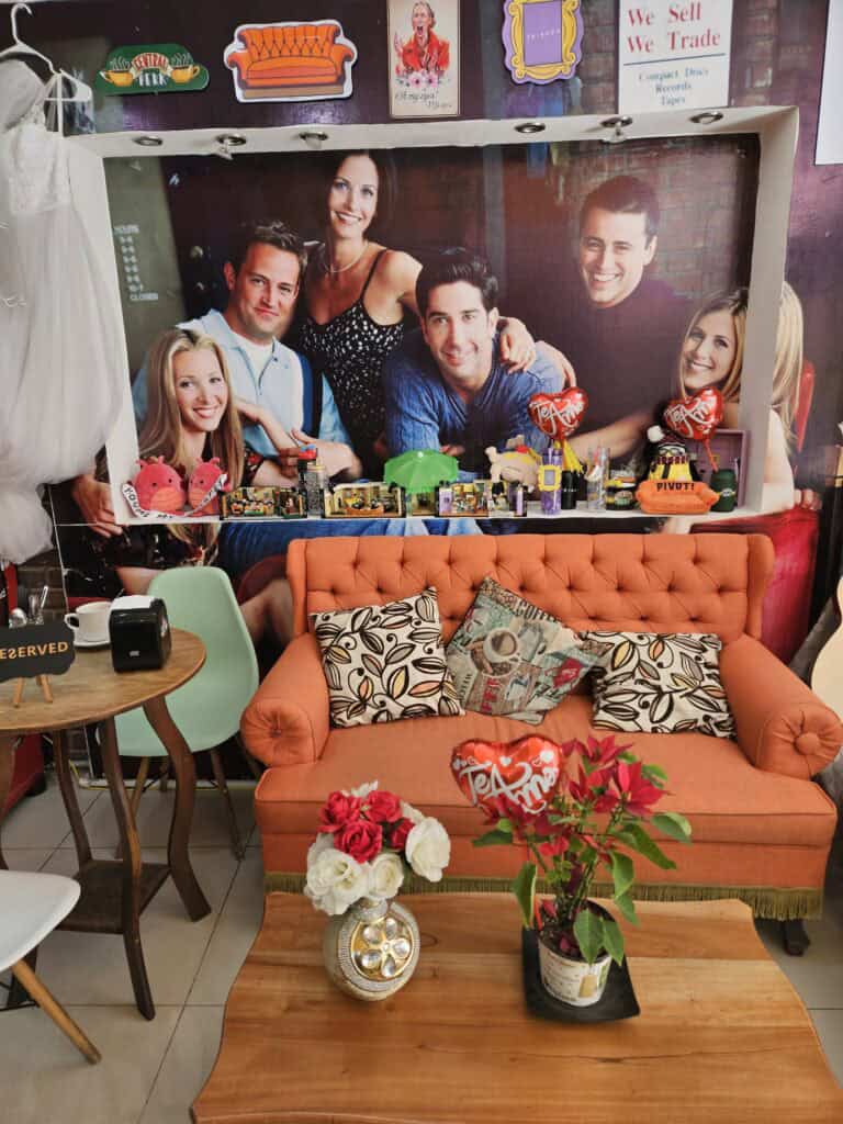 Interior of Friends coffee cafe complete with orange sofa and photo of the Friends show cast.