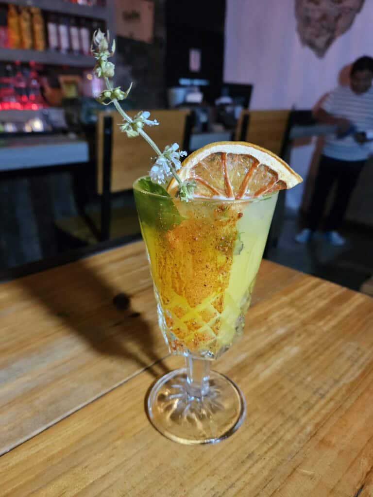 Photo of yellow cocktail in a tall glass at a Mezcaleria bar in Merida Mexico