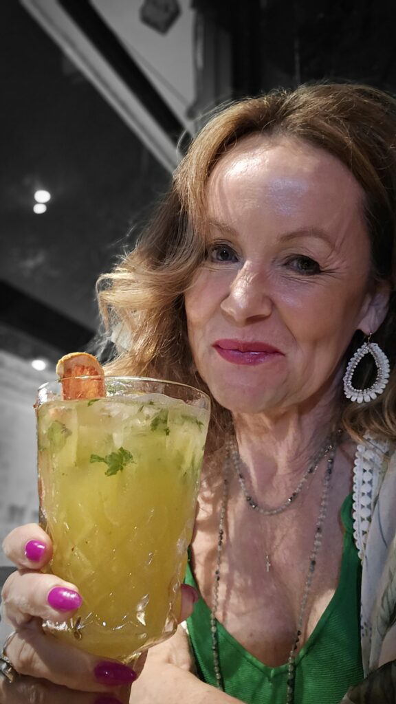 Me having a Mezcal cocktail vibrant yellow and green in Merida Mexico