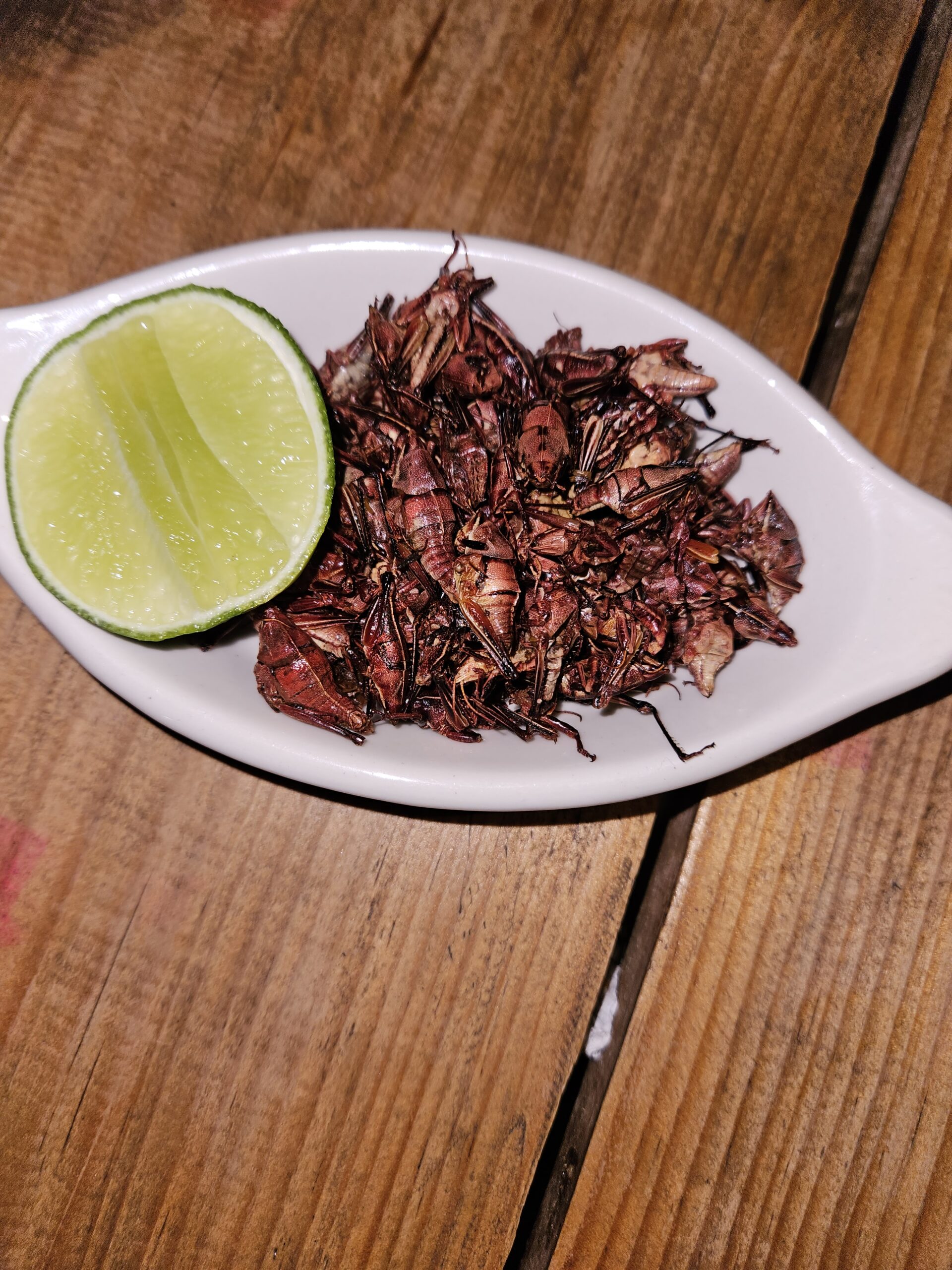 A plate or chapulines or grasshoppers served with a side of lime