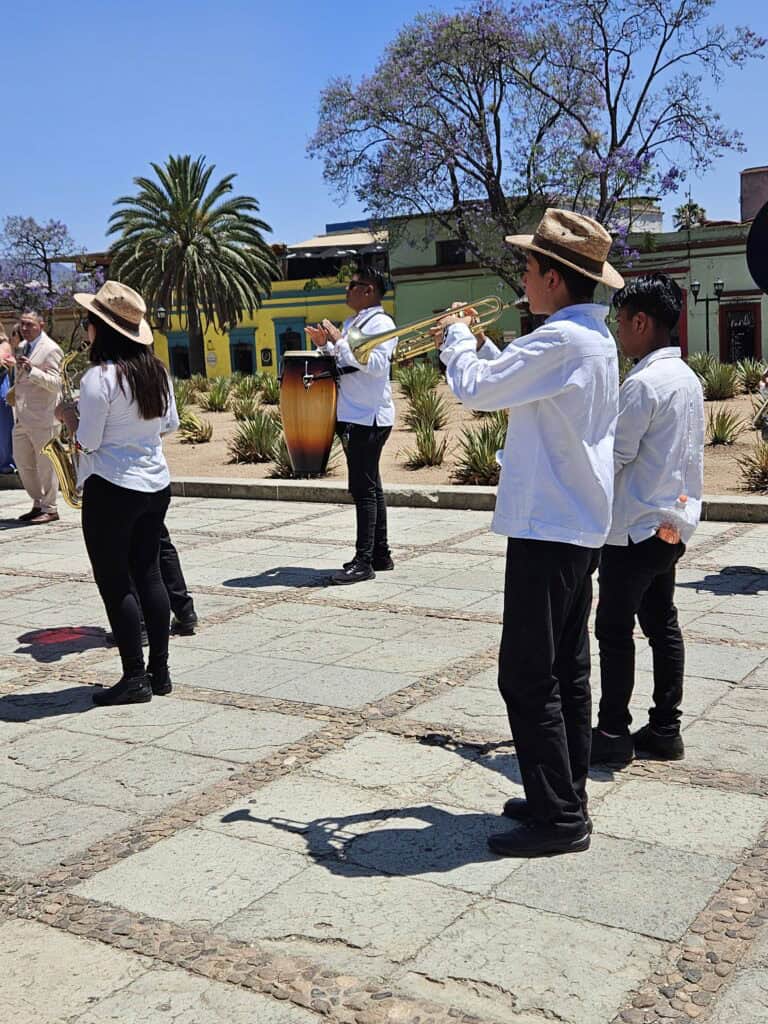 Musicians dressed in white shirts and black pants who are part of a wedding celebration and parade outside of the Templo de Santo Domingo de Guzman in Oaxaca Mexico