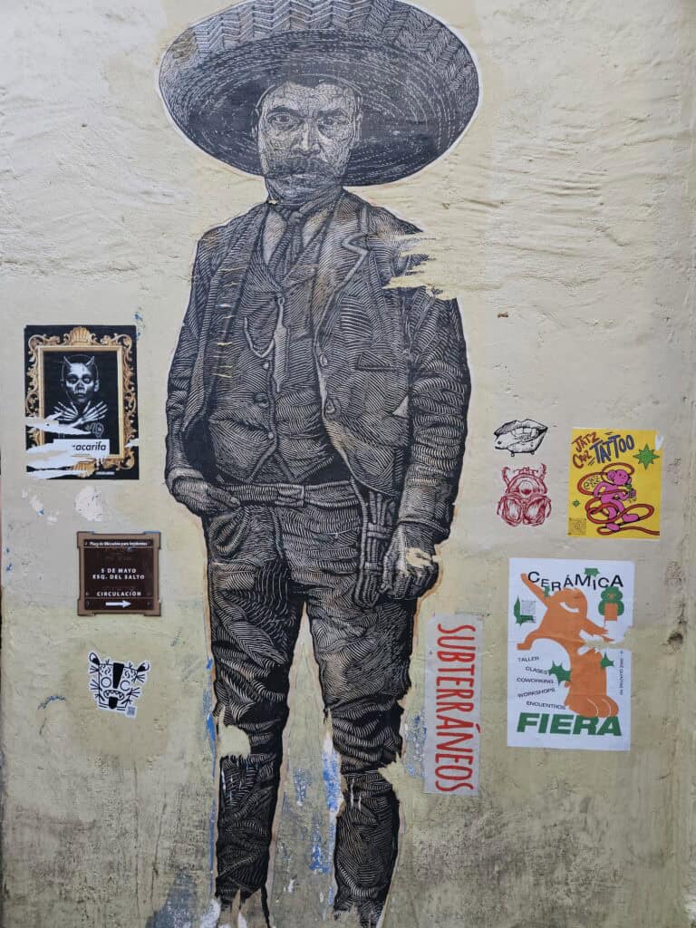 Print of Mexican man with large hat and gun belt seen on a wall in Oaxaca Mexico