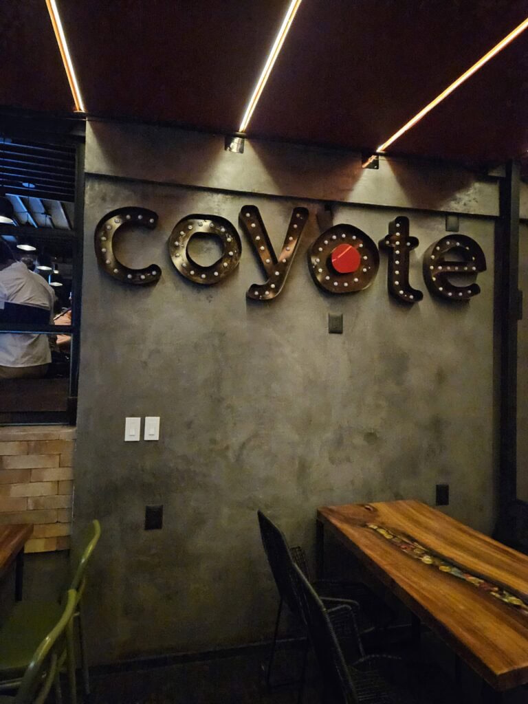 Coyote for the restaurant in black letters lit up with a red circle in the middle of the 2nd o