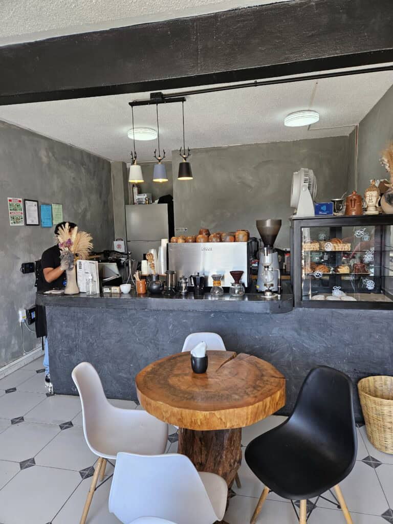 Interior view of counter, wooden tables, and white and black chairs in Finca El Olivo