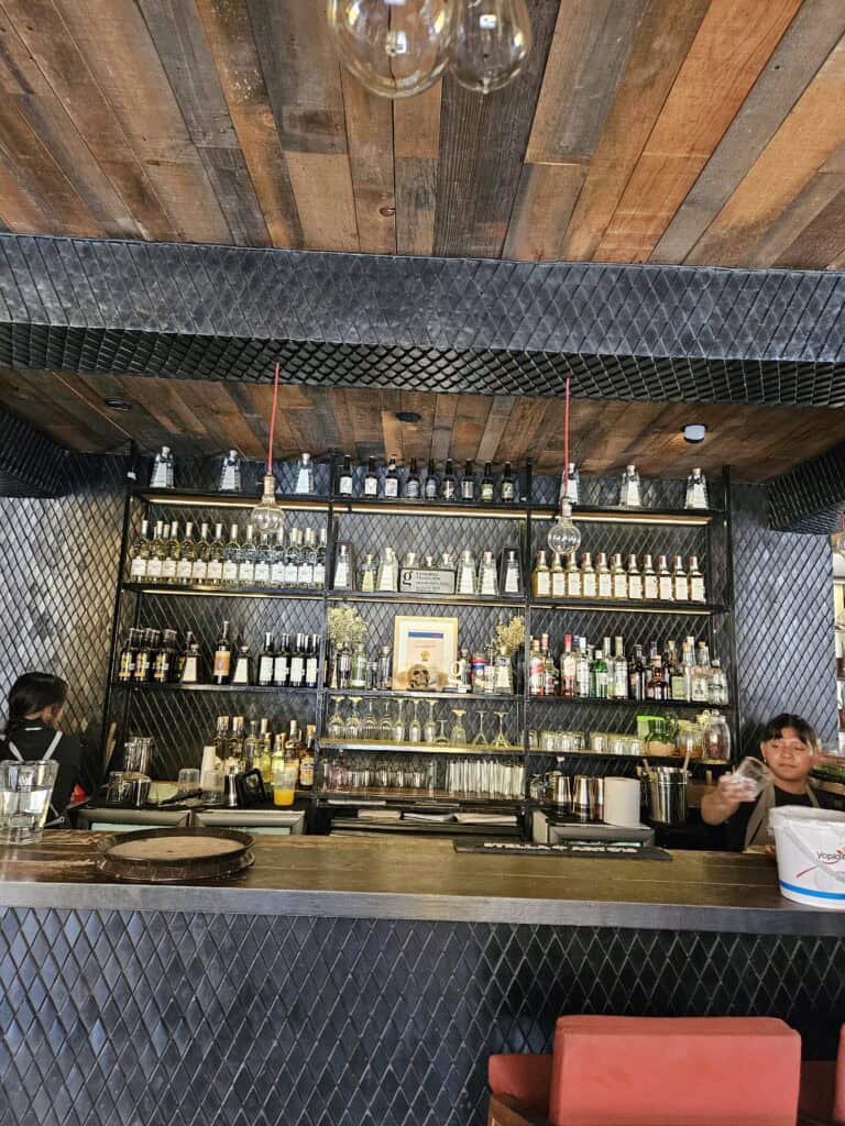 Bar view of Oaxacan Restaurant, four shelves of liquor options.