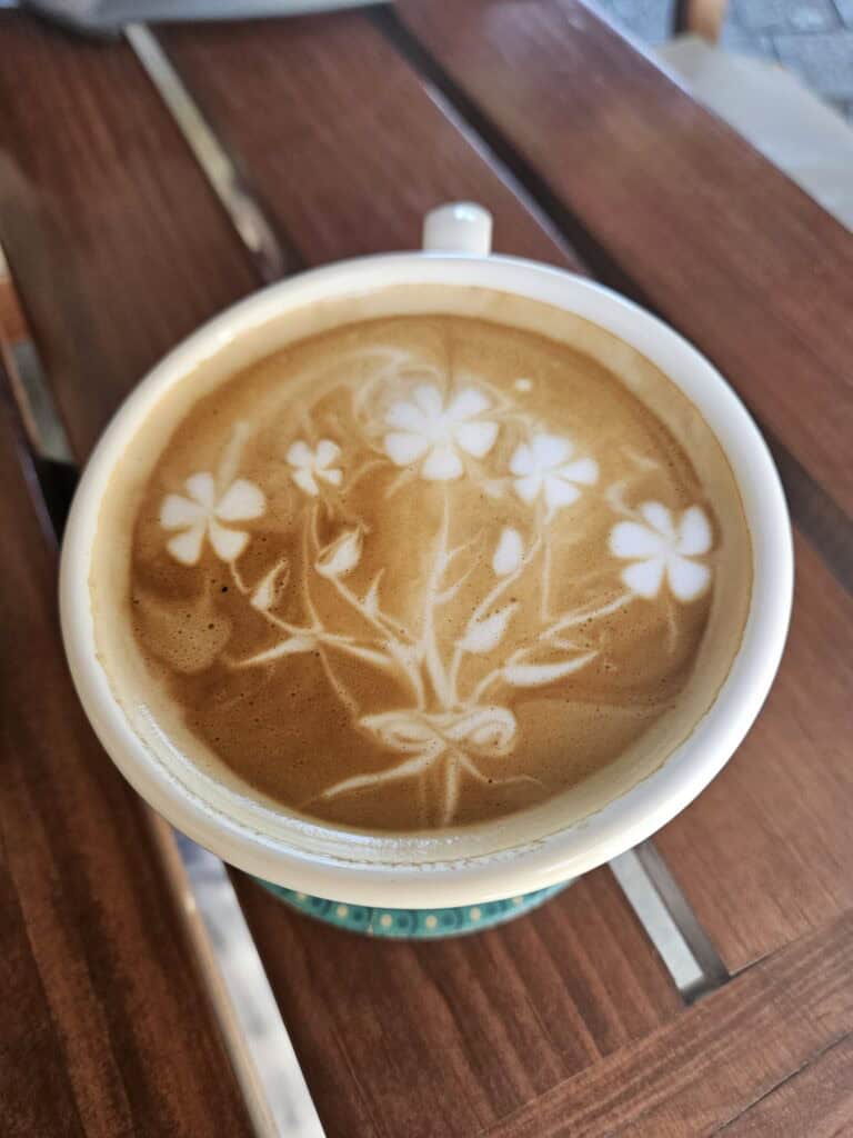 A cup of coffee with tiny flowers designed into the foam