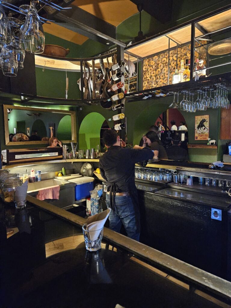 Bar at El Olive restaurant in Oaxaca Mexico. The bartender is pouring a drink.