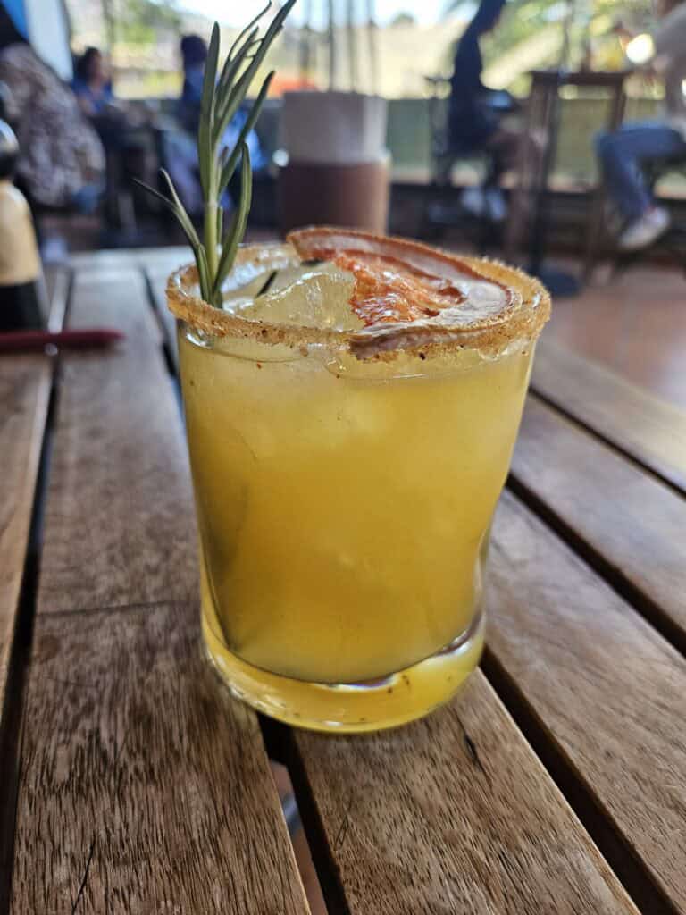Mezcal cocktail with a tajin rim and a sprig of rosemary