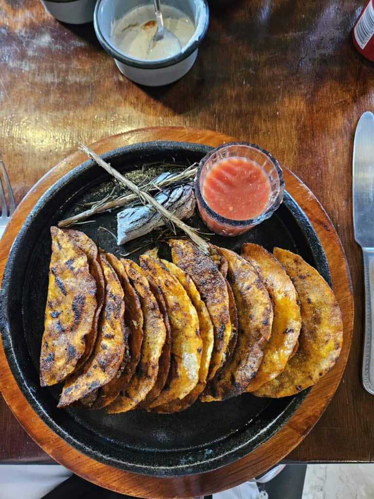 Tacos on a black plate with a side of salsa