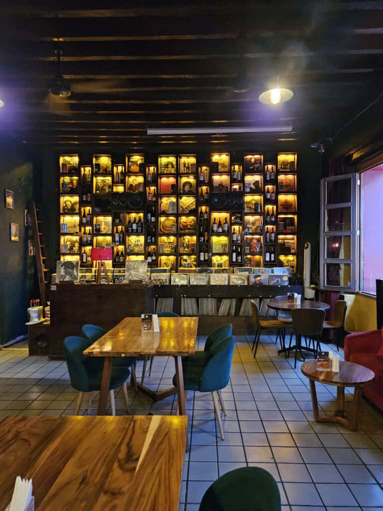 Interior view of Vino & Vinyl wine bar in Oaxaca Mexico with a view of the shelf of wine bottles and vinyl albums