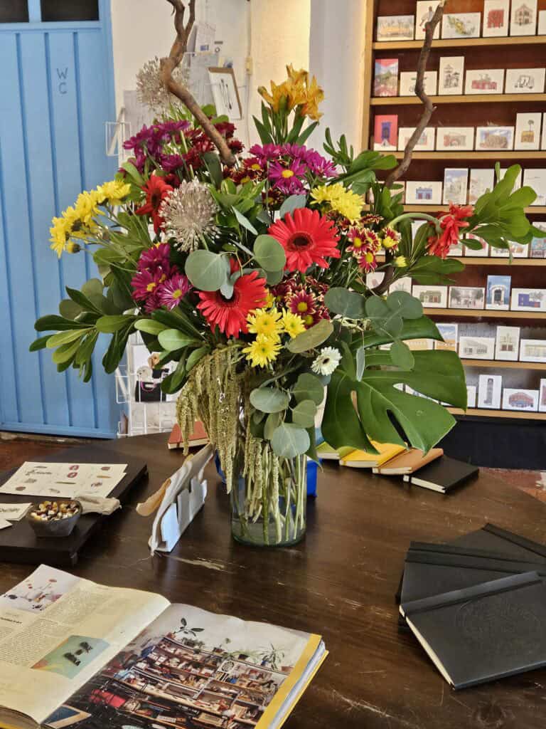 Bouquet of flowers in colors of yellow, pink, and red with large greenery as a center piece in Once in Oaxaca Cafe
