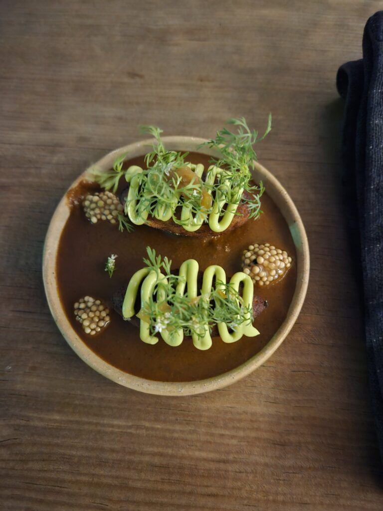 White bowl with dish as part of five course tasting menu at Nois Restaurant in Oaxaca Mexico