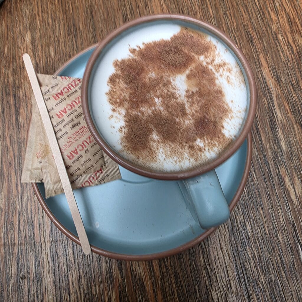 Acappucino with cinnamon on top in a blue cup and saucer