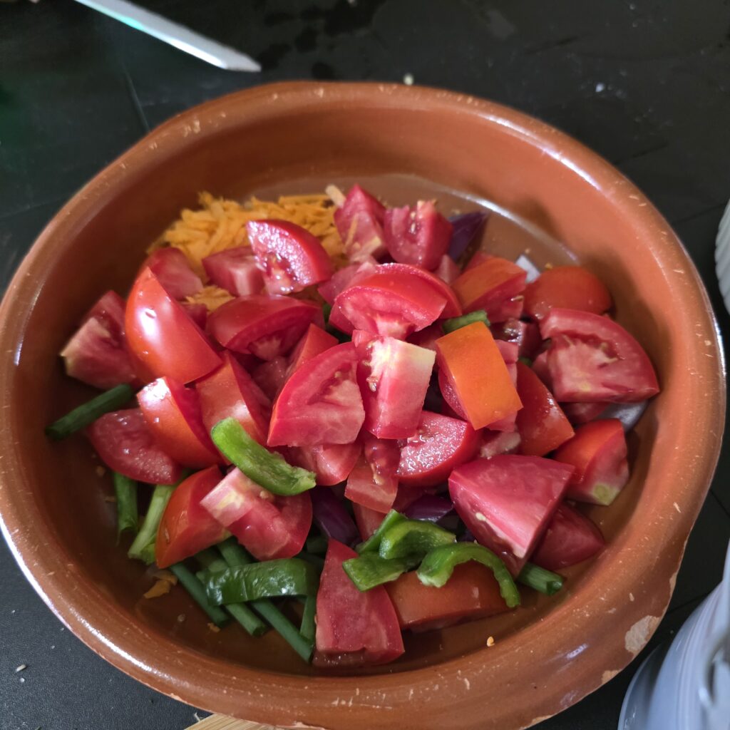 Bowl of tomatoes and other ingredients with bits of green