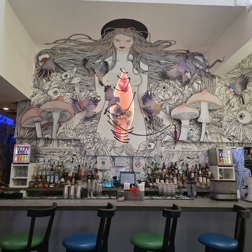 Mural of a woman and mushrooms on wall and ceiling behind the bar at Tantalo Rooftop Bar in Casco Viejo Panama