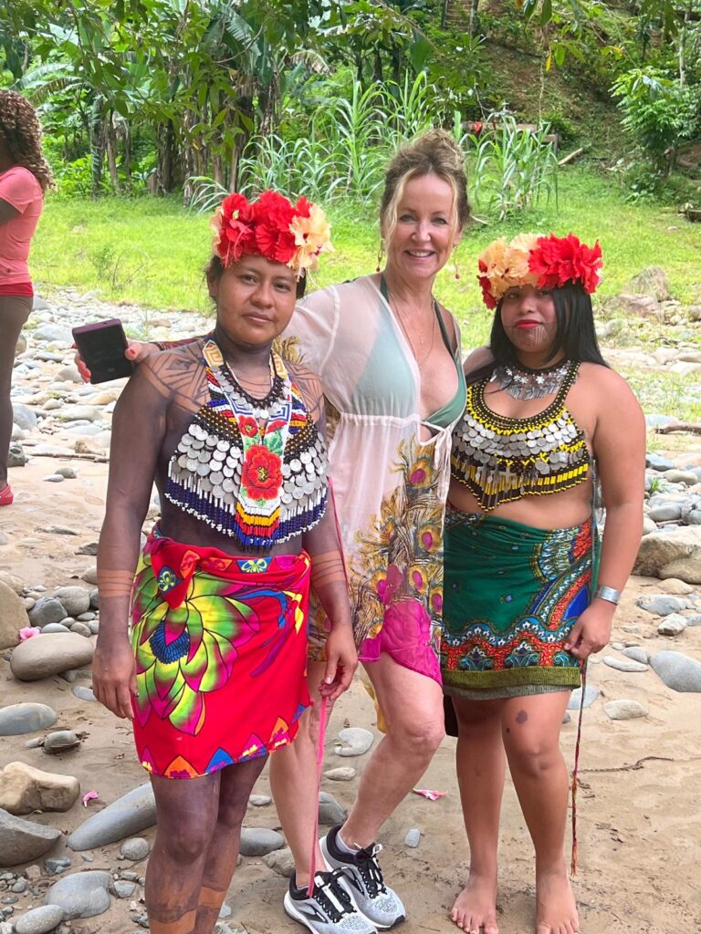 Me posing with two colorfully dressed Embera woman while visitn gtheir village in Panama