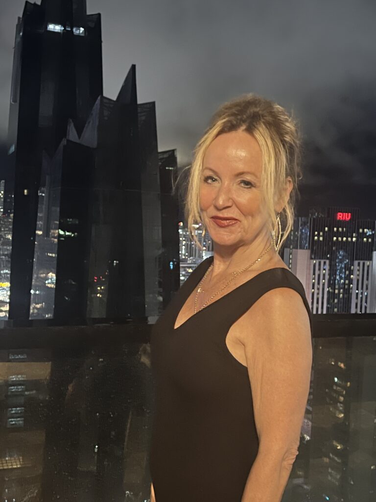 Me in a black dress on a rooftop bar overllooking the nightime skyline in Panama City Panama
